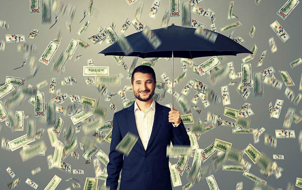 Man holding umbrella under money rain.