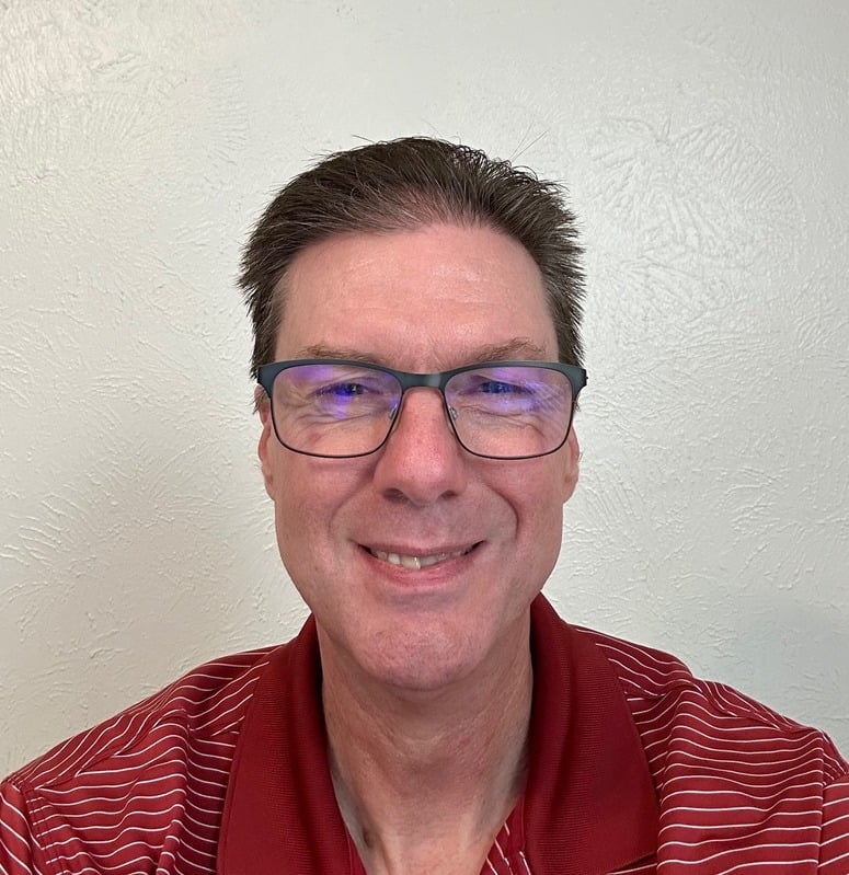 Smiling man wearing glasses and red shirt.