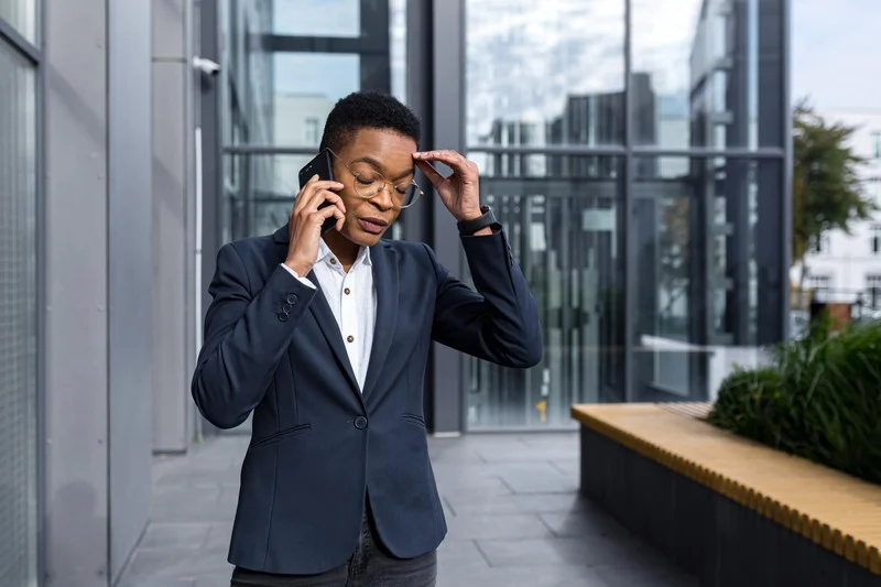 Woman in suit talking on phone outside building.